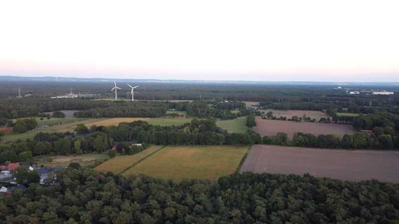 Weiter Blick über Felder und Wälder mit Windrädern im Abendlicht