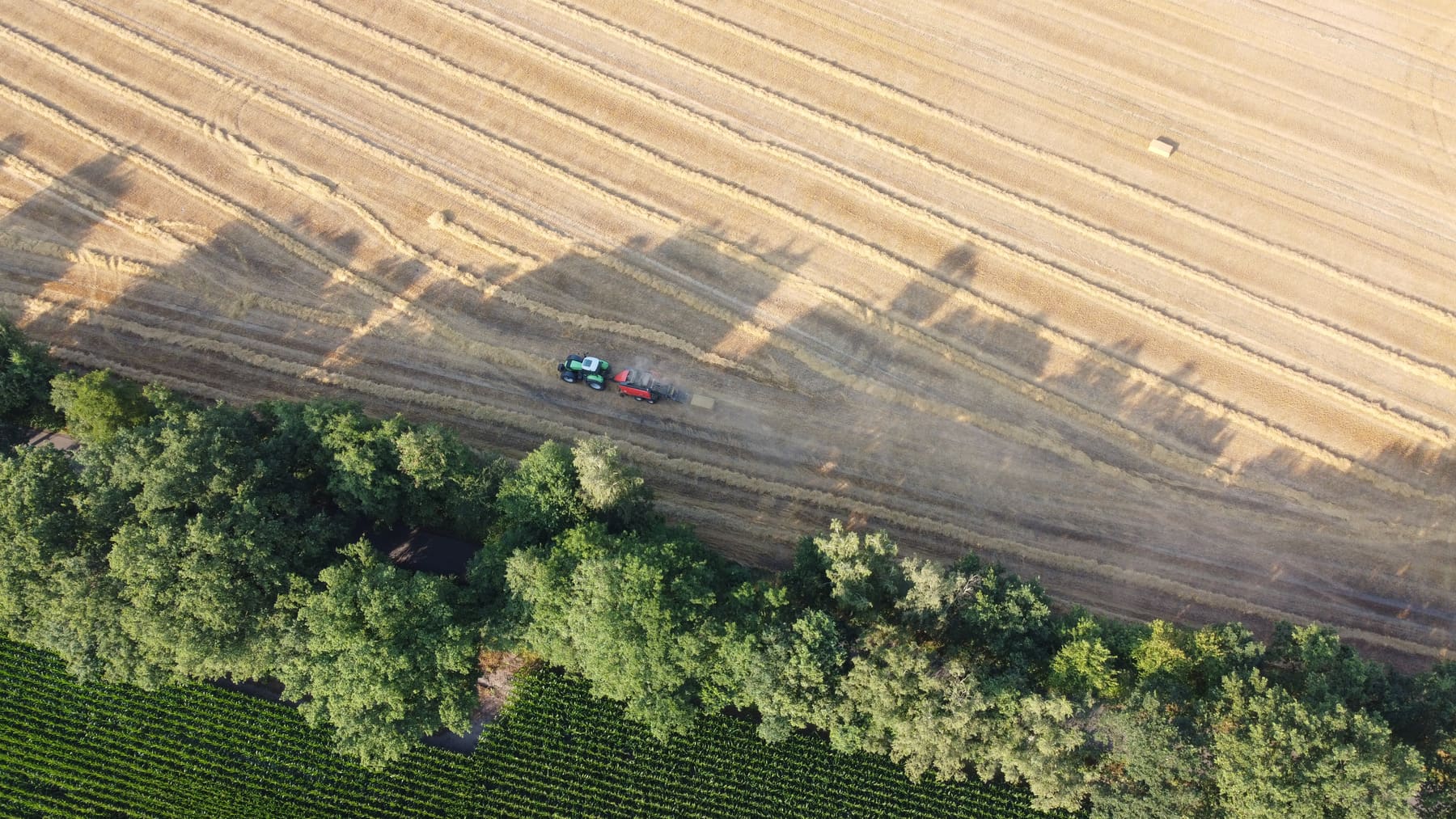 Traktor mit Ballenpresse auf dem Stoppelfeld aus der Vogelperspektive